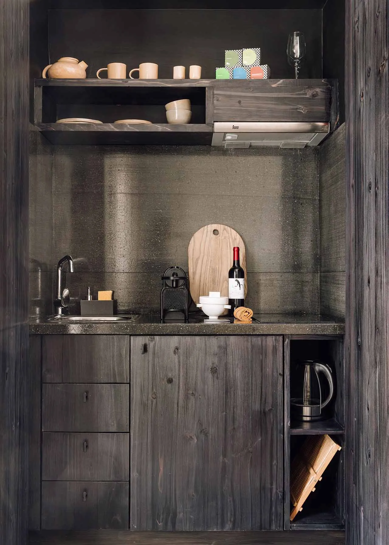 A modern, minimalist residential kitchen featuring wooden cabinets and a concrete countertop.