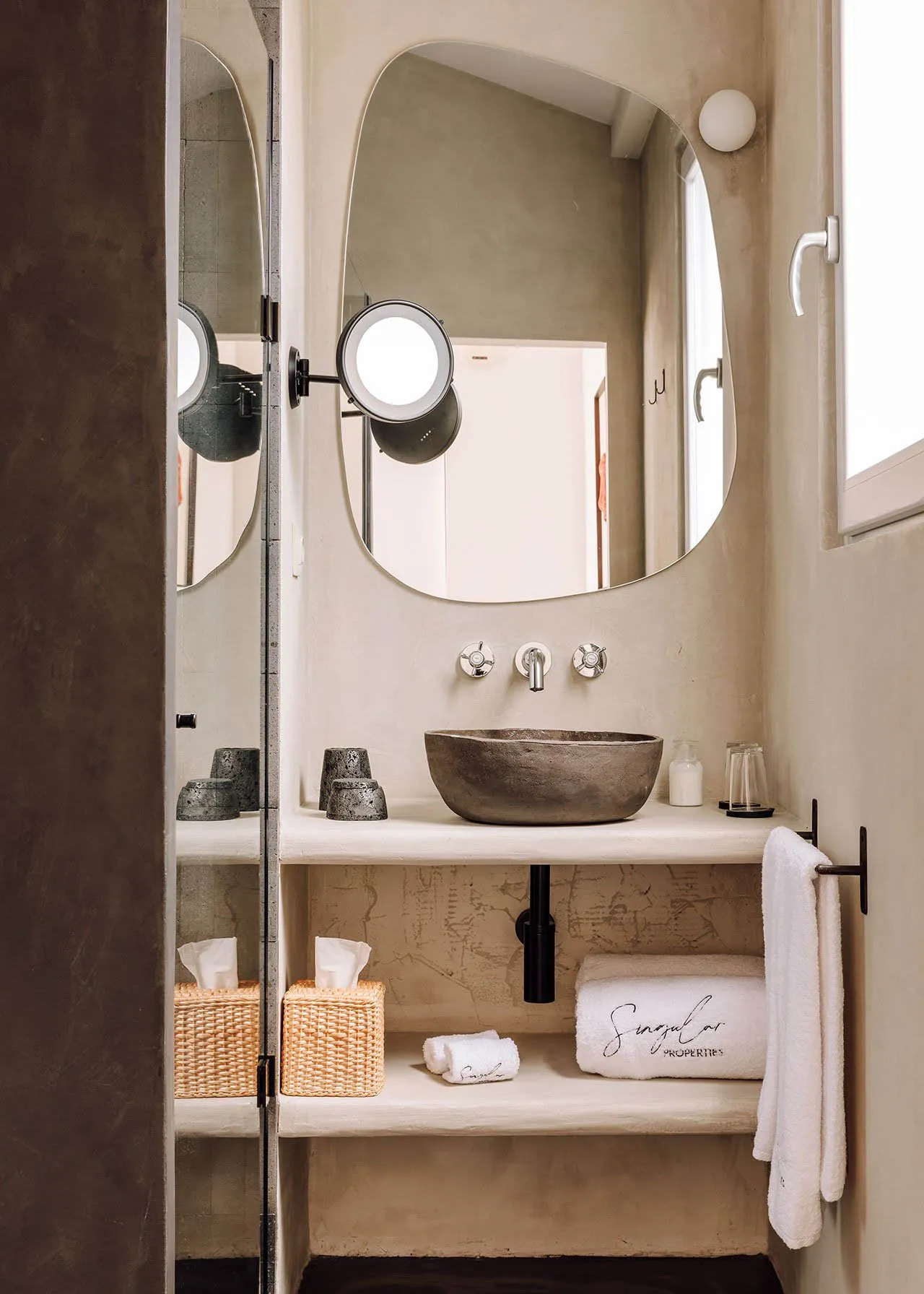Minimalist bathroom with a concrete countertop and sink, white towels, and decorative elements.