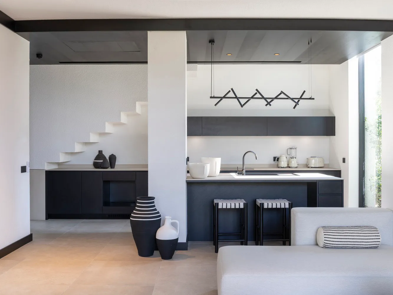 Modern kitchen with black and white color scheme and stone countertops.