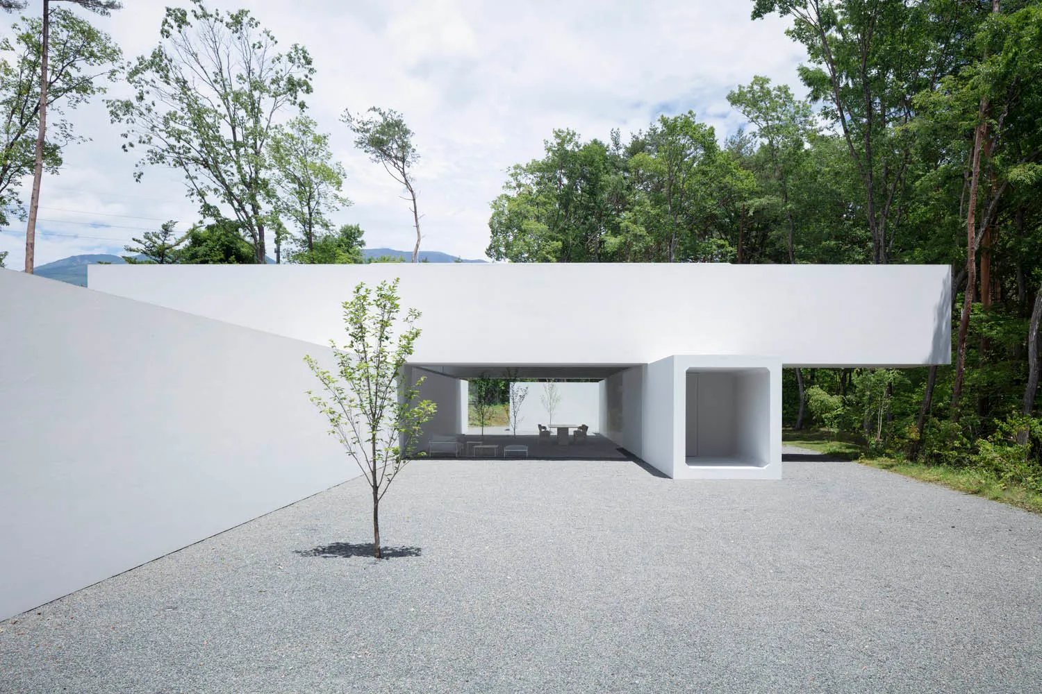 A modern exterior platform made of concrete with trees and mountains in the background.