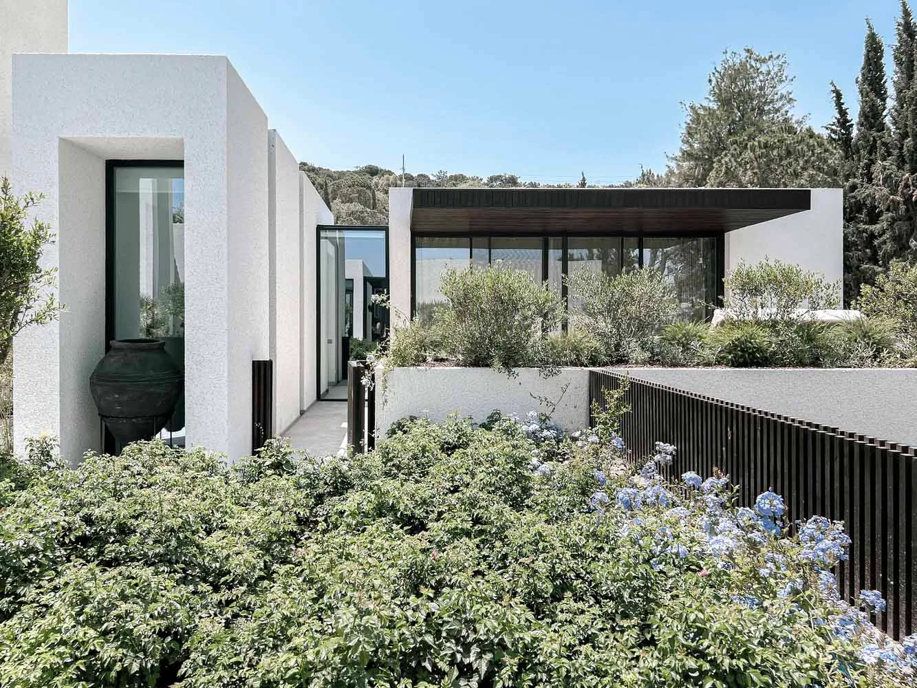 Modern residential home with white concrete exterior and large glass windows.