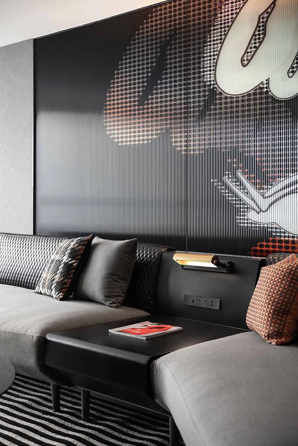 Modern living room with fabric sofa, leather accents, metal wall paneling, and graphic wall art