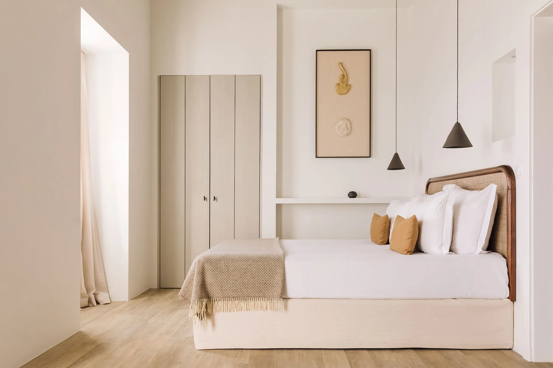 A modern minimalist bedroom featuring a bed with a wooden headboard, white bedding, and wooden flooring.