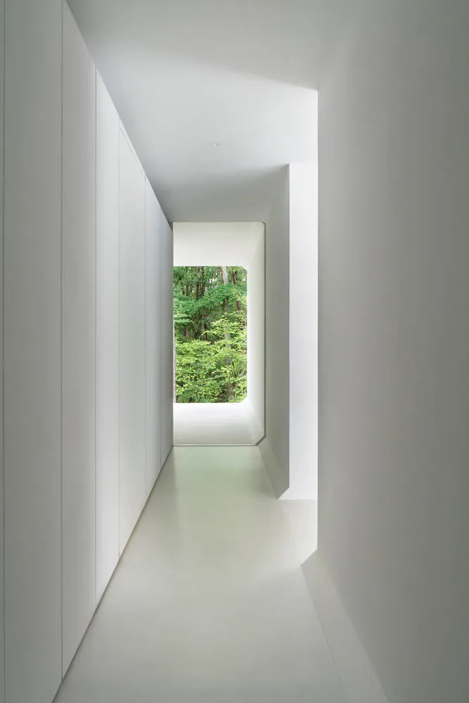 Minimalist corridor with white walls, concrete floor, and steel elements.
