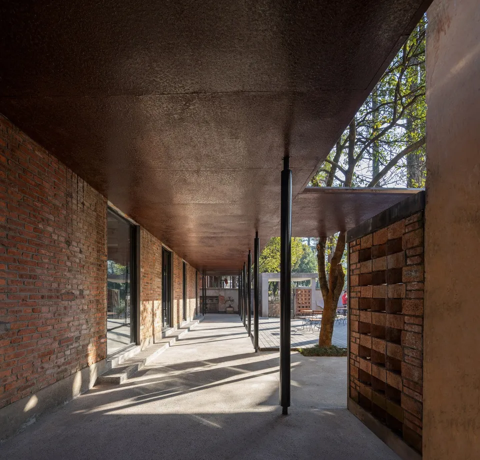 Outdoor pavilion with brick walls, concrete floor, and steel columns.