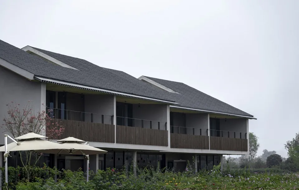 Modern residential building with a wooden balcony and glass windows.