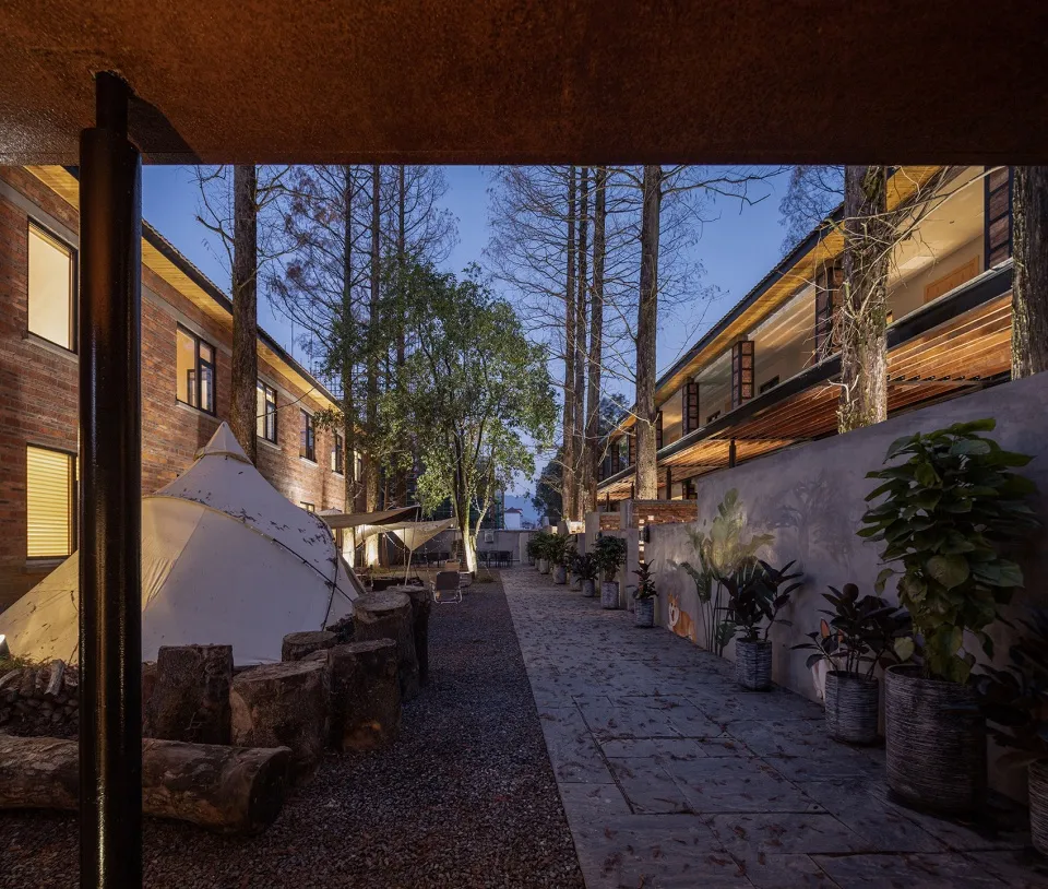 A residential building with brick walls, wooden accents, and concrete paths at twilight.