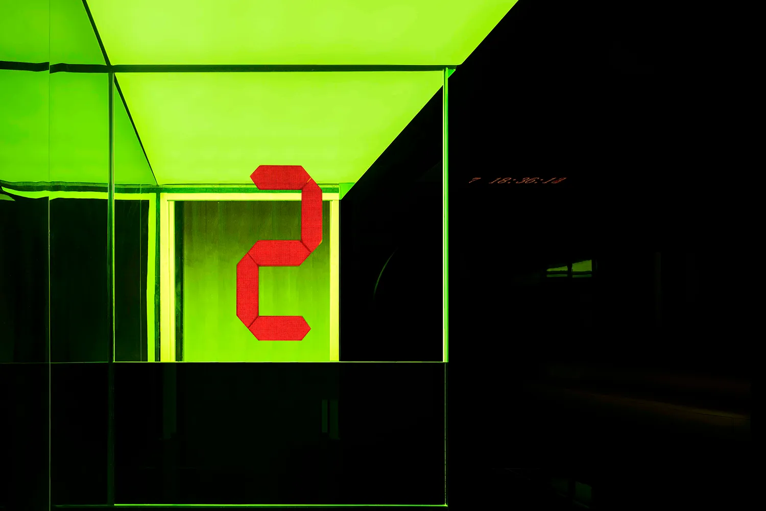 A digital display showing the number 2 in red, illuminated against a bright green background.