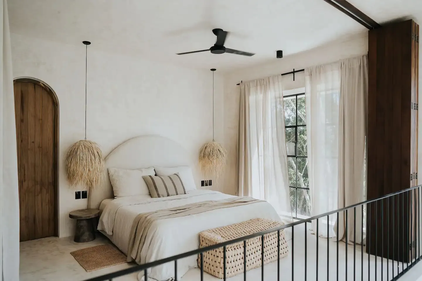 A minimalist bedroom with a bed, curtains, and a ceiling fan.