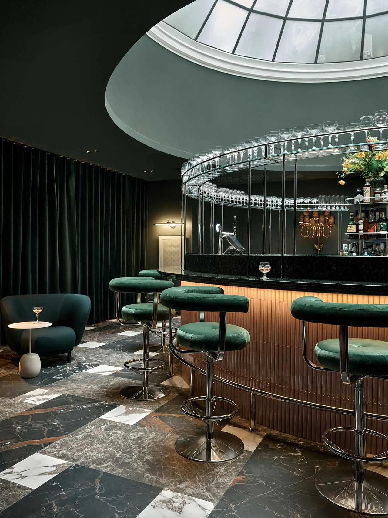 Bar with green stools, marble flooring, and dark green curtains.