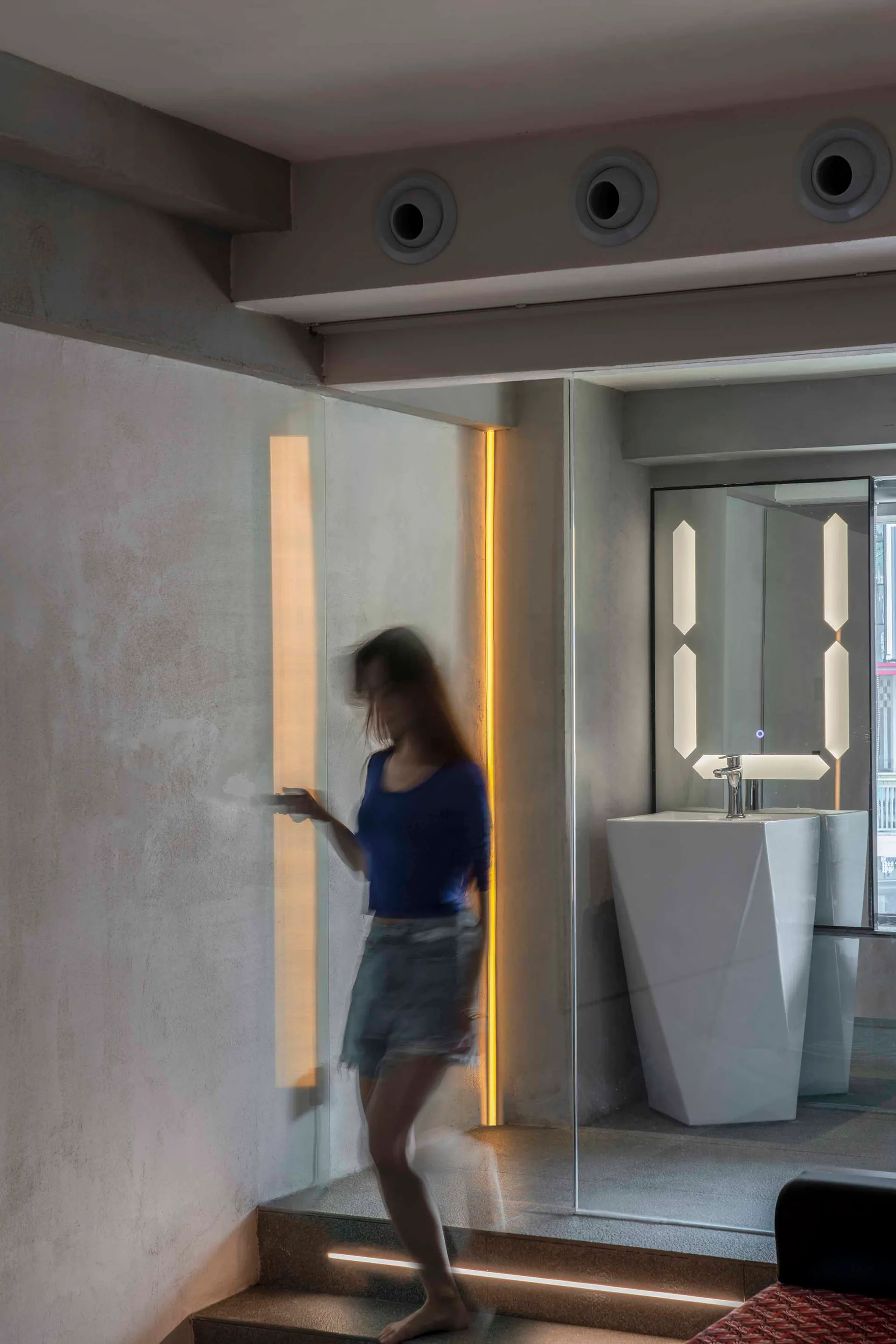 A modern bathroom featuring concrete, glass, and stainless steel materials with an open space design.