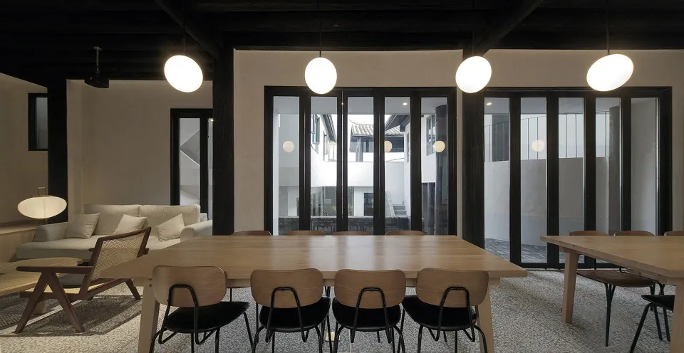 Modern dining room with wooden tables, fabric chairs, and glass walls