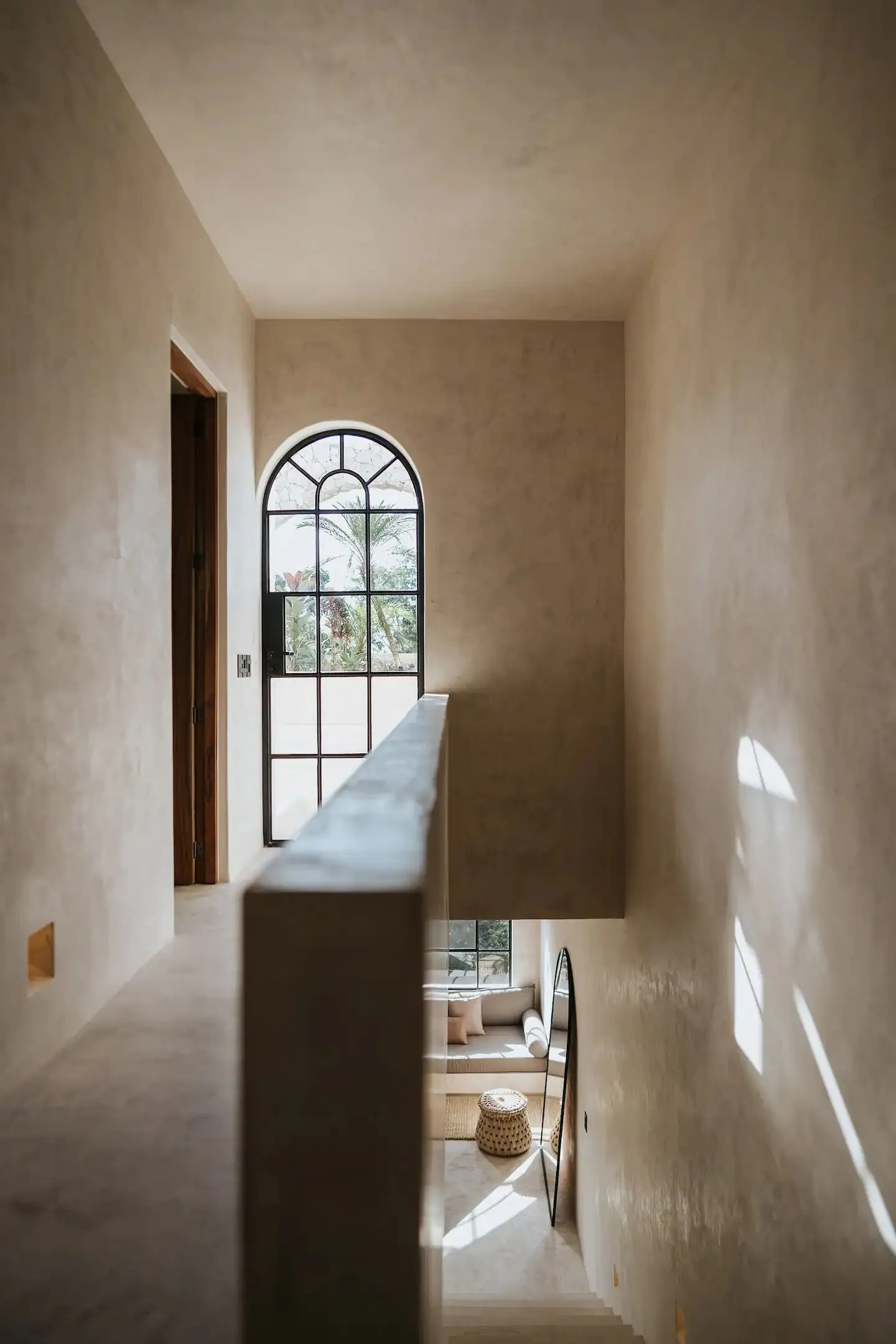 Modern residential stairwell with concrete and plaster walls featuring a lighting panel.