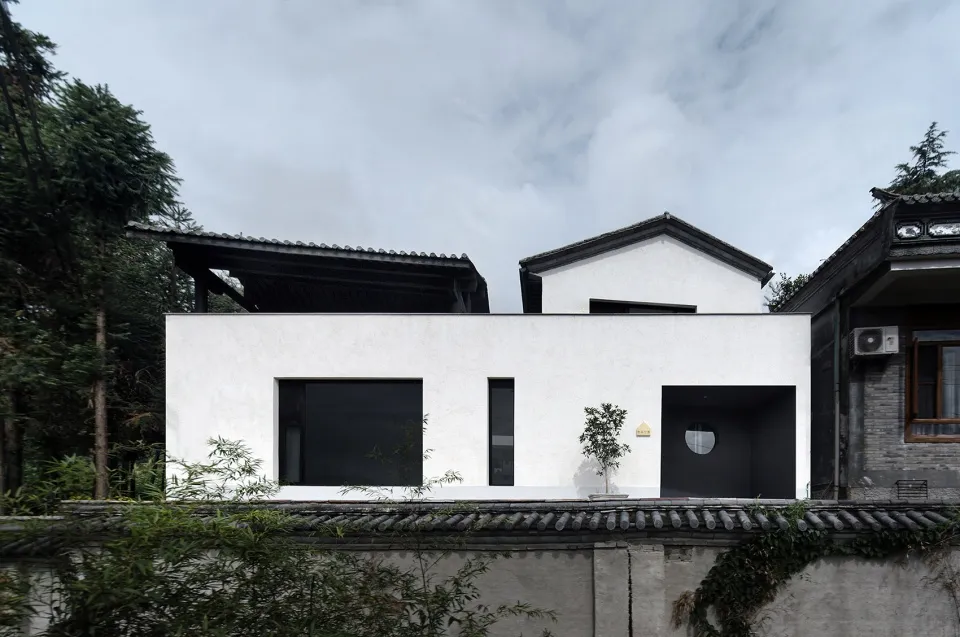 A modern house with a white exterior featuring glass windows and a flat roof.