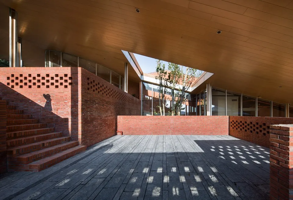 Modern outdoor courtyard space featuring brick walls, wooden flooring, and glass elements.