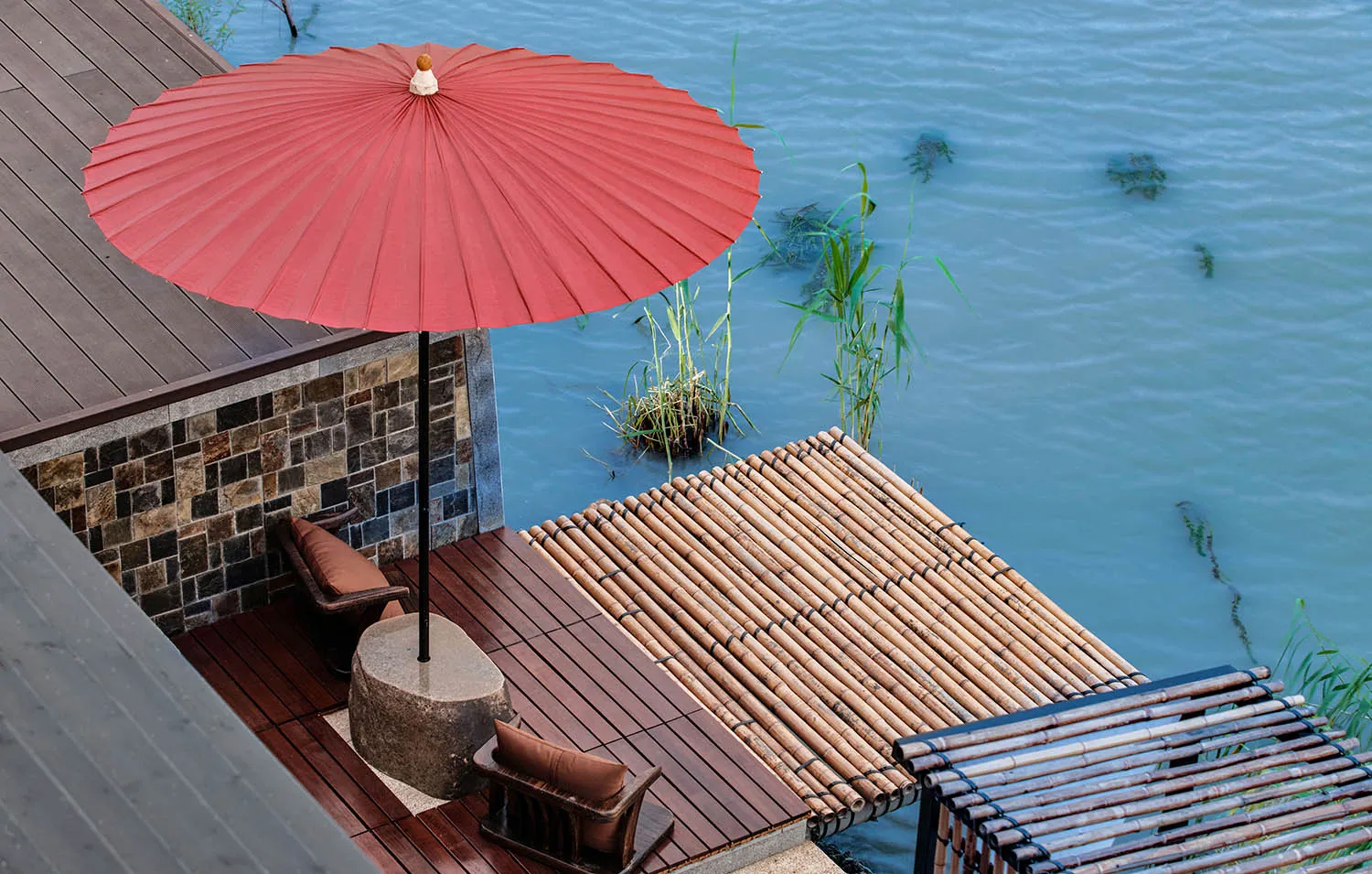 A minimalist terrace with a wooden platform overlooking water.