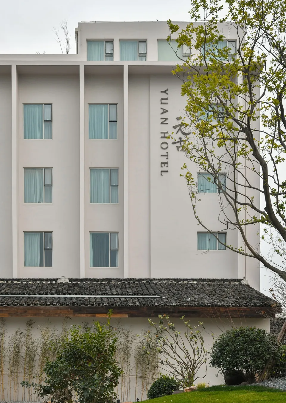 Modern hotel building with a white facade and grey concrete roof.