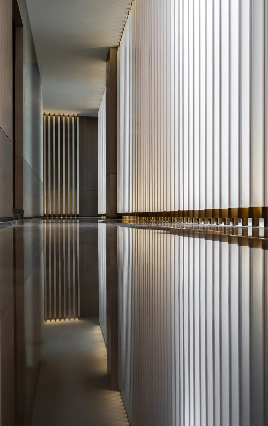 A modern interior featuring glass columns reflected in a polished floor.