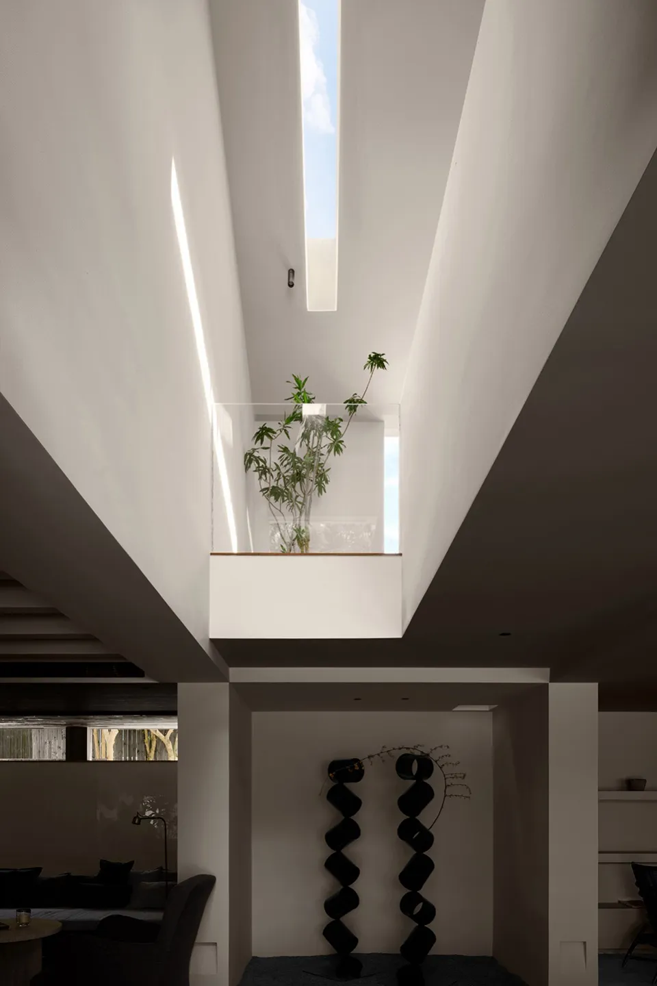 A minimalist living room featuring concrete walls and large windows with a view of the sky.