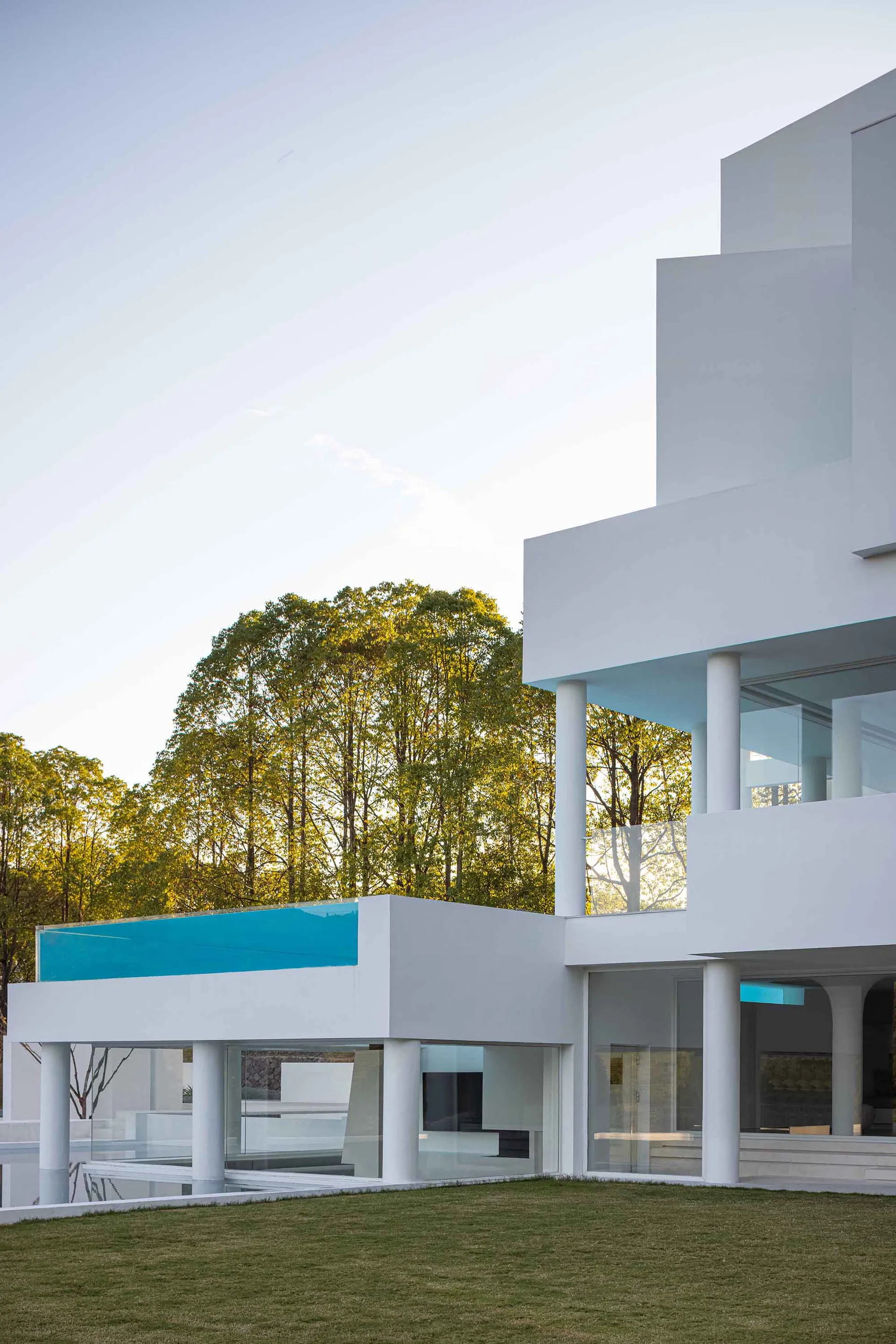 A modern house with large glass walls and white columns