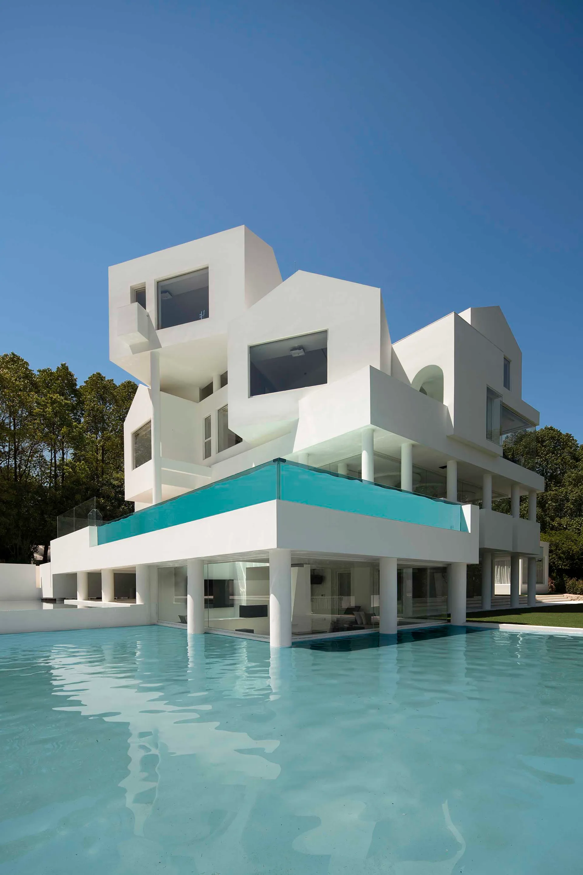 Contemporary residential building with minimalist design, primarily constructed from white concrete, glass, and steel.