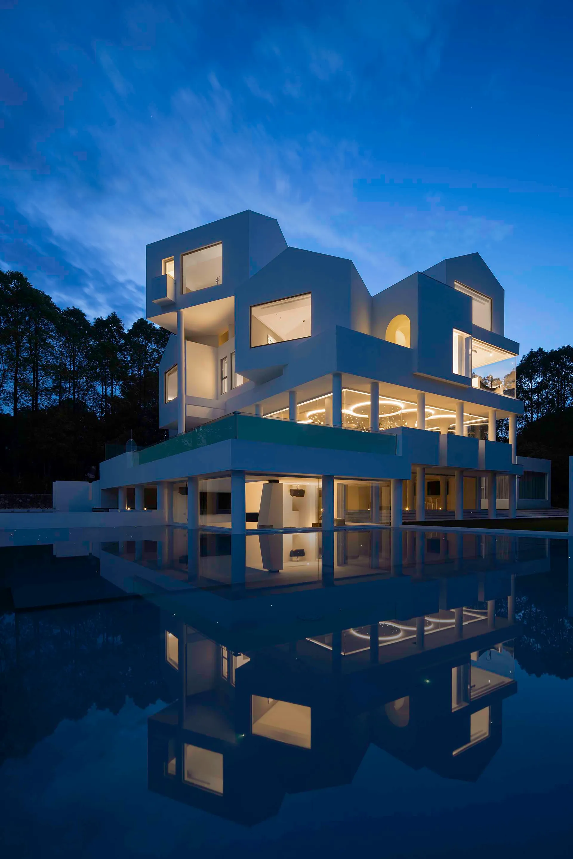 Modern residential house with glass walls and illuminated interior in twilight