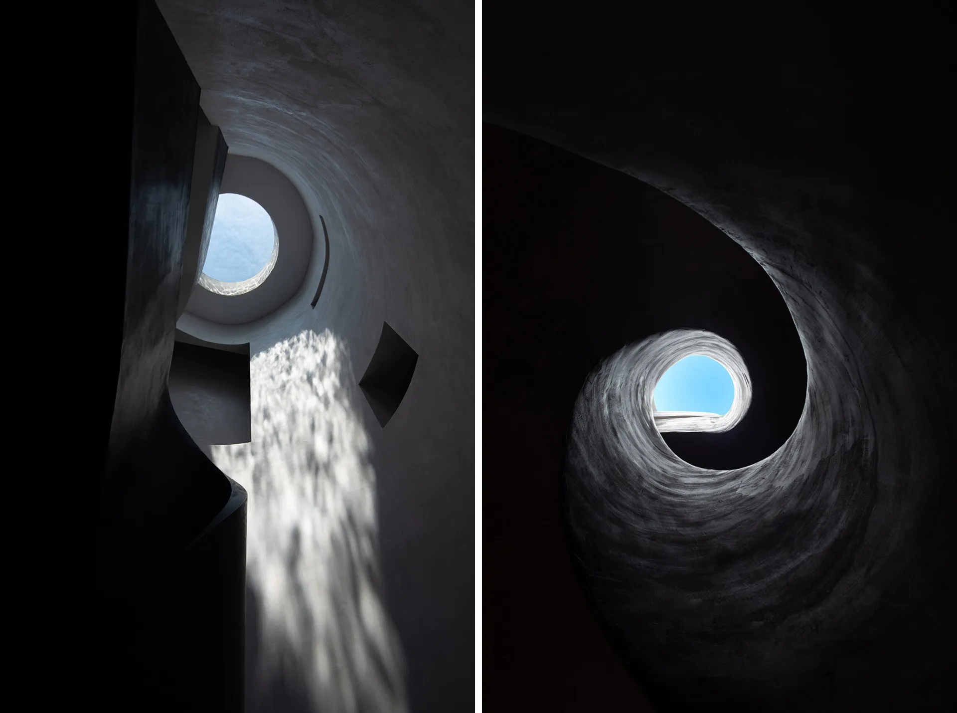 A circular, concrete staircase with a central skylight, leading upwards in a spiral pattern.