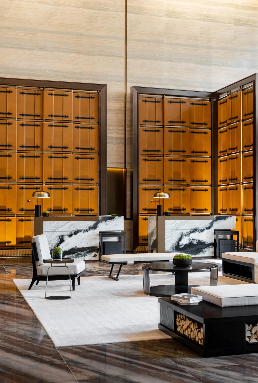 Modern, minimalist lobby with marble walls, wood furniture, and white seating.
