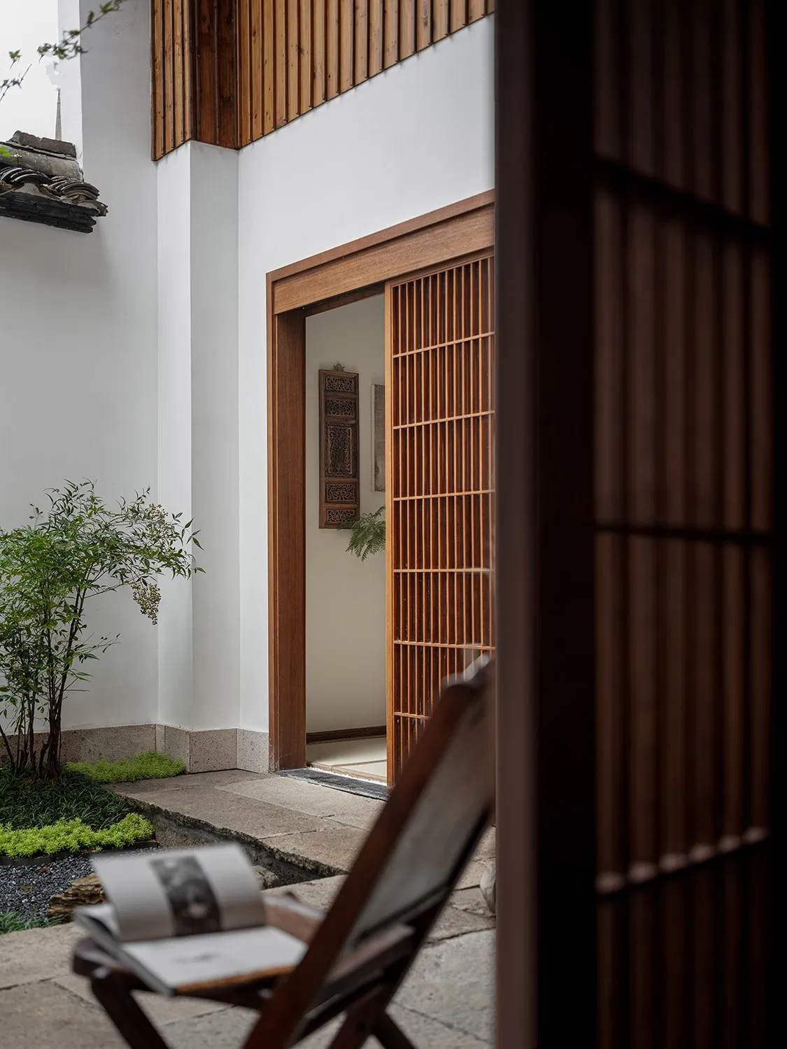 A traditional-style entryway garden with wooden elements and a open door.