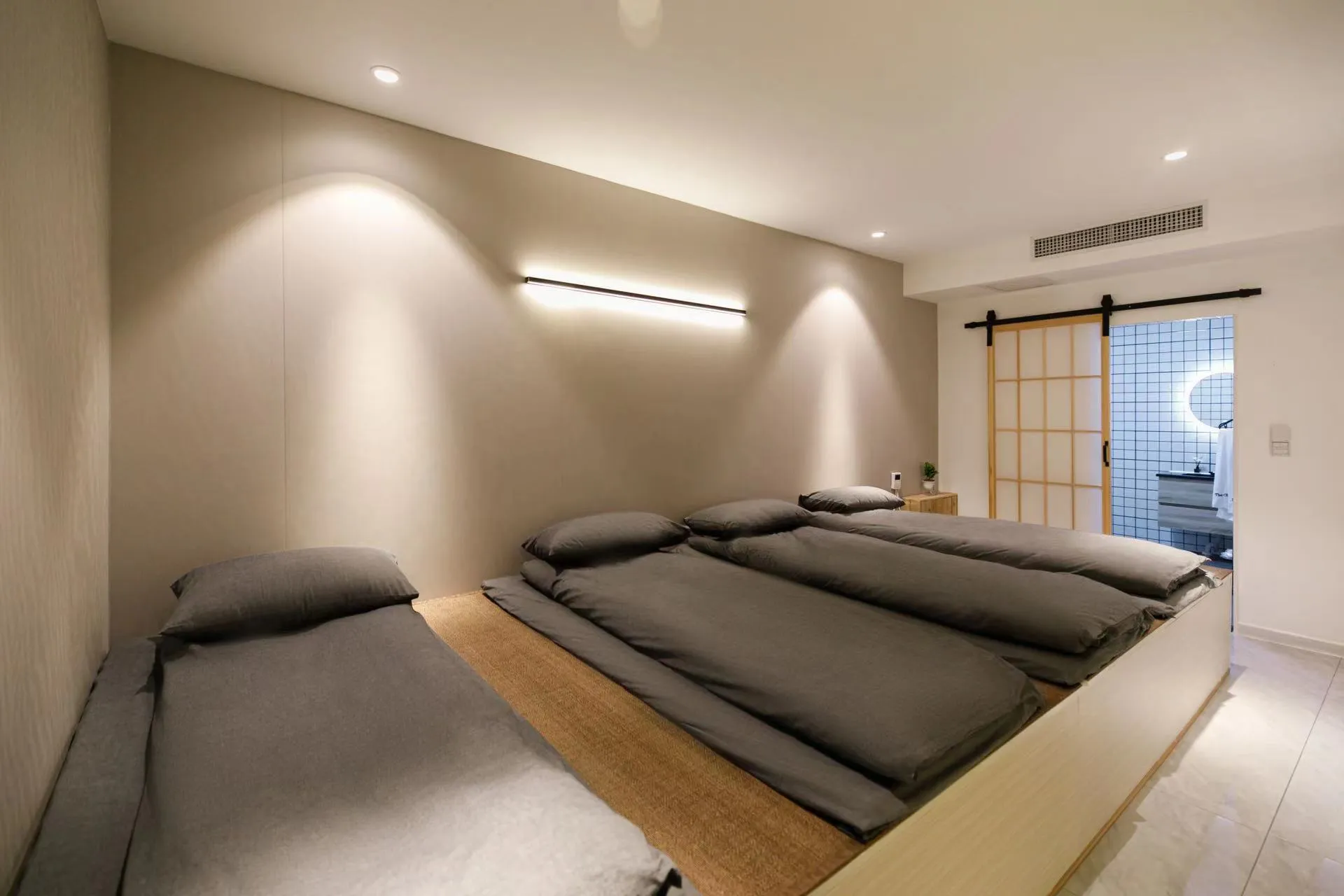 A minimalist bedroom with grey beds and wooden accents.