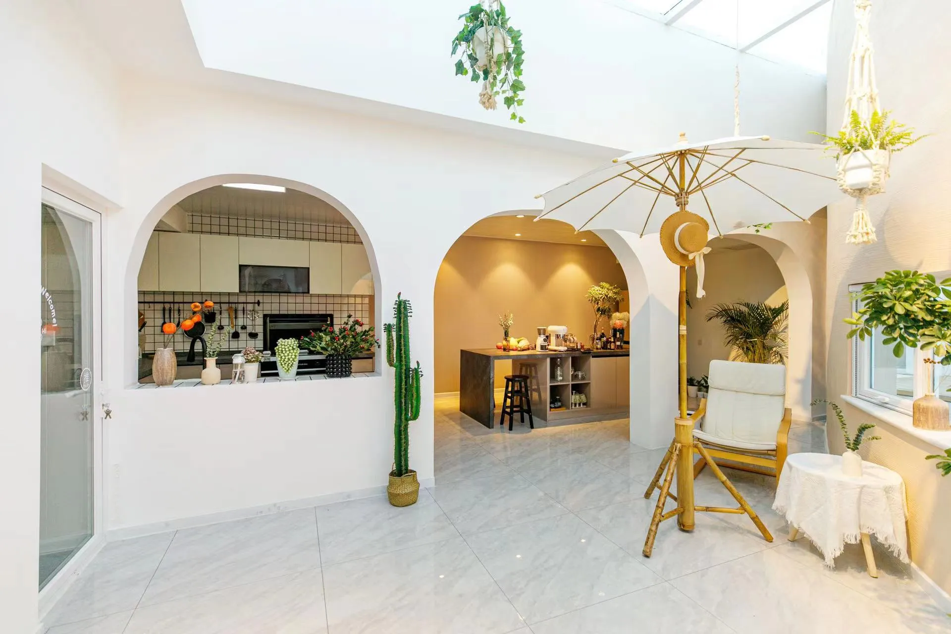 A minimalist kitchen with concrete flooring and walls, featuring modern appliances and a central island with bar stools.