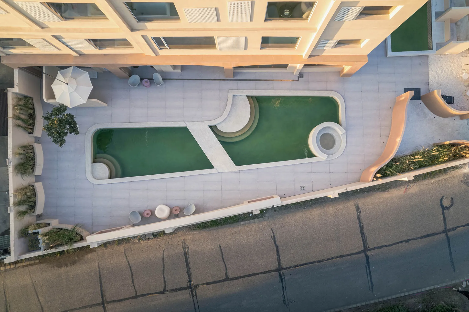 Modern minimalist swimming pool area with green water and concrete poolside.