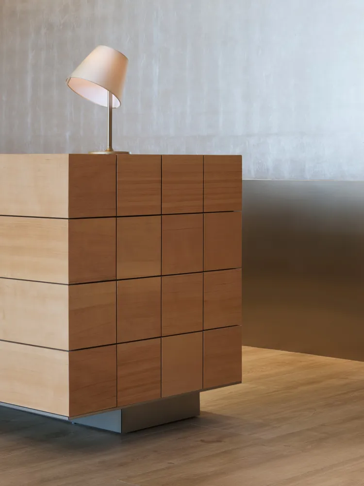 A modern wooden sideboard with a table lamp on top, set against a minimalist background.