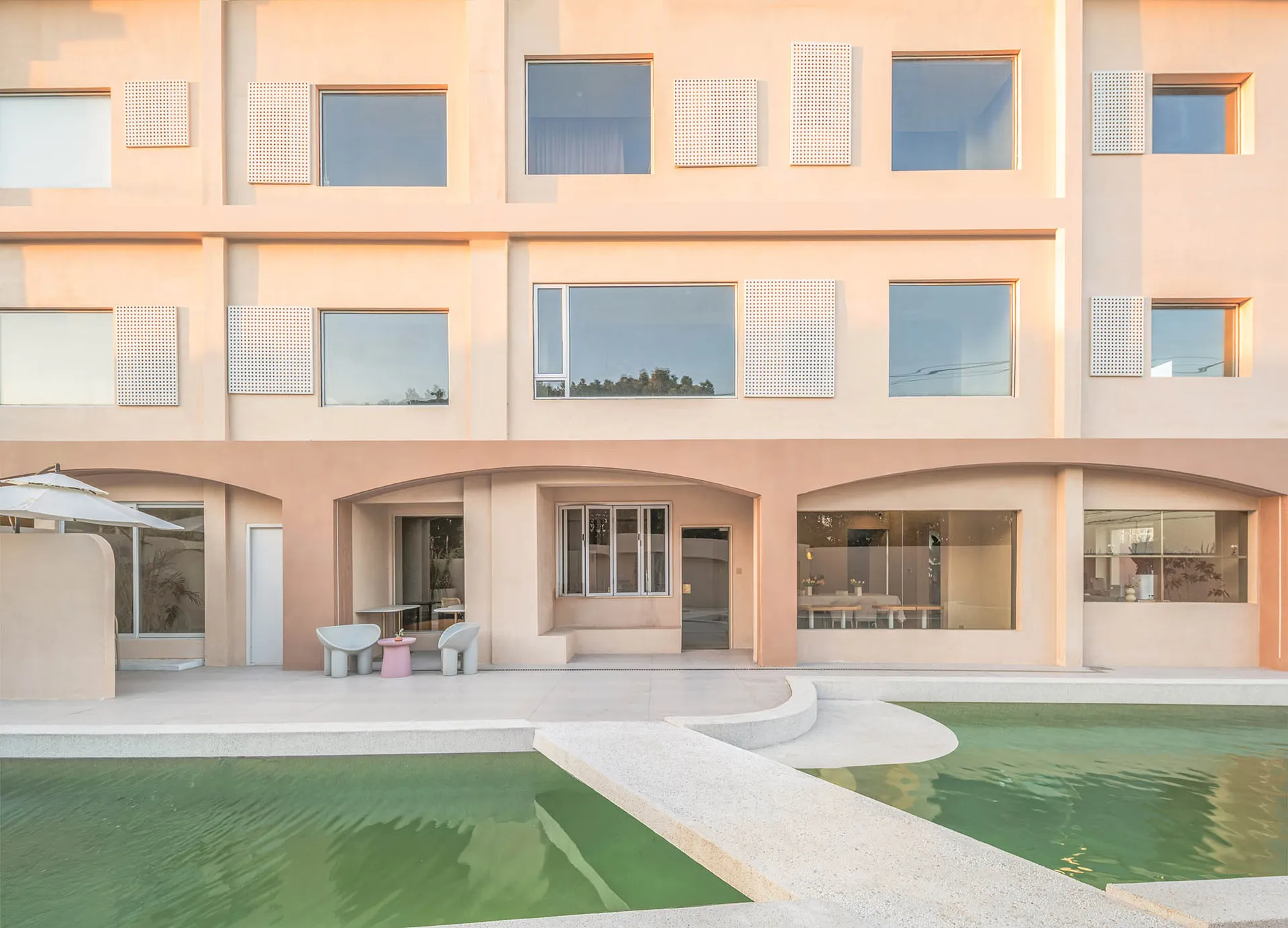 A minimalist residential building with a concrete exterior and a swimming pool.
