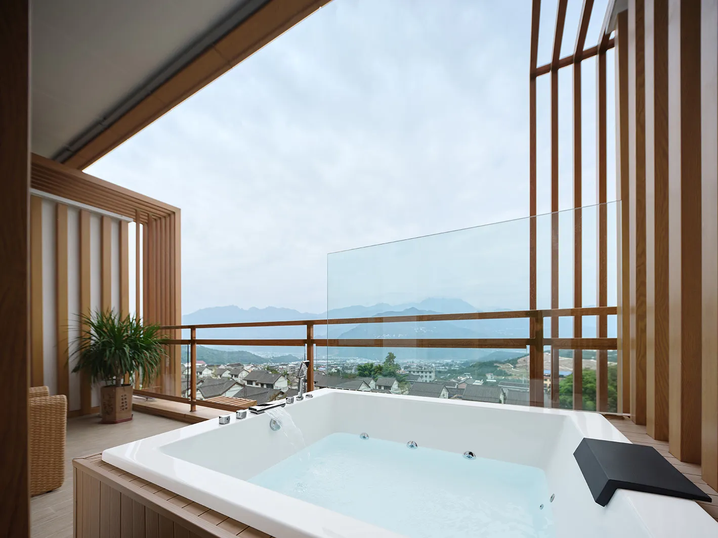 A modern bathroom featuring a glass hot tub with a view of a town and mountains.