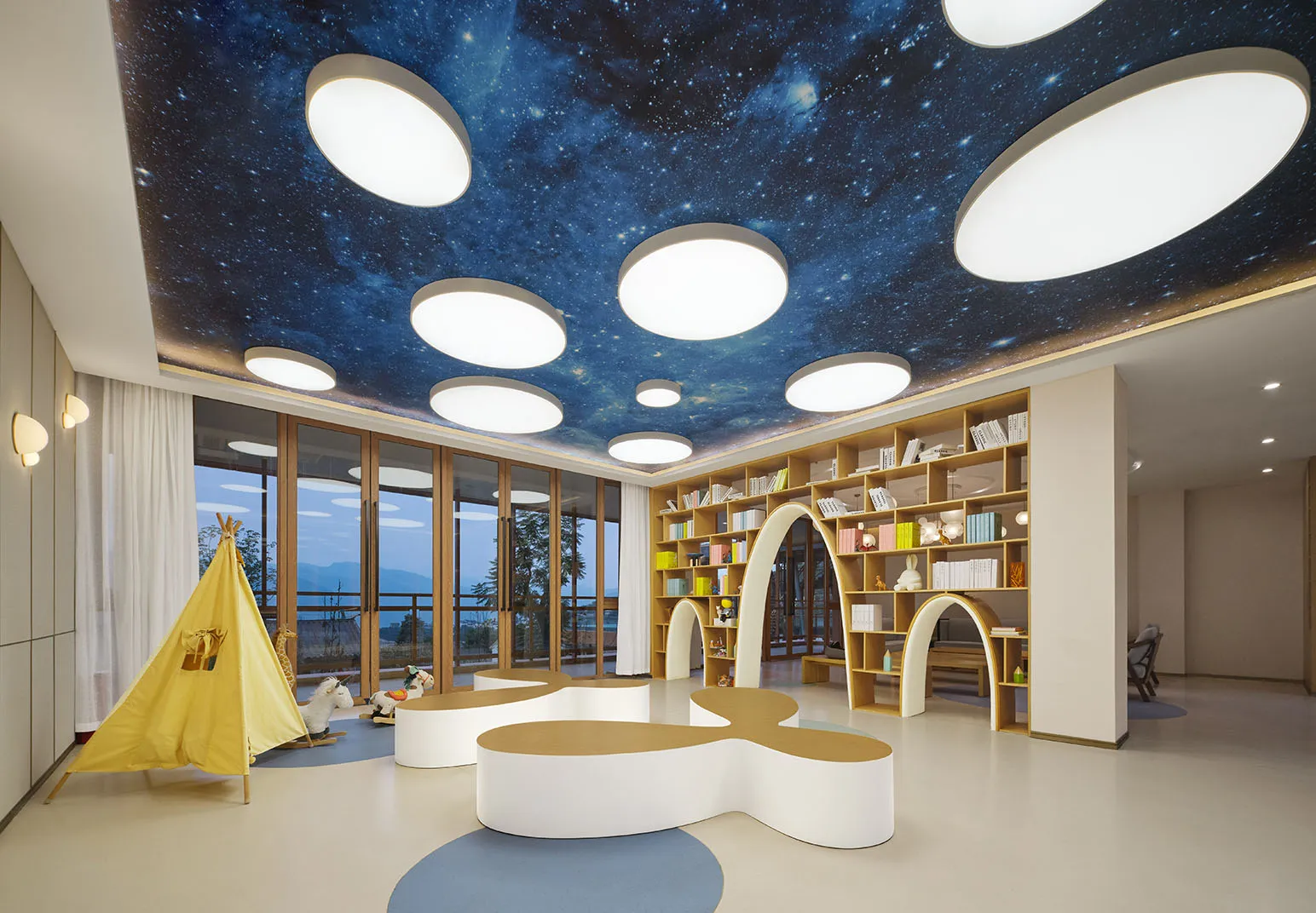 A modern playroom with a wooden floor, fabric seating, and a galaxy-themed ceiling.