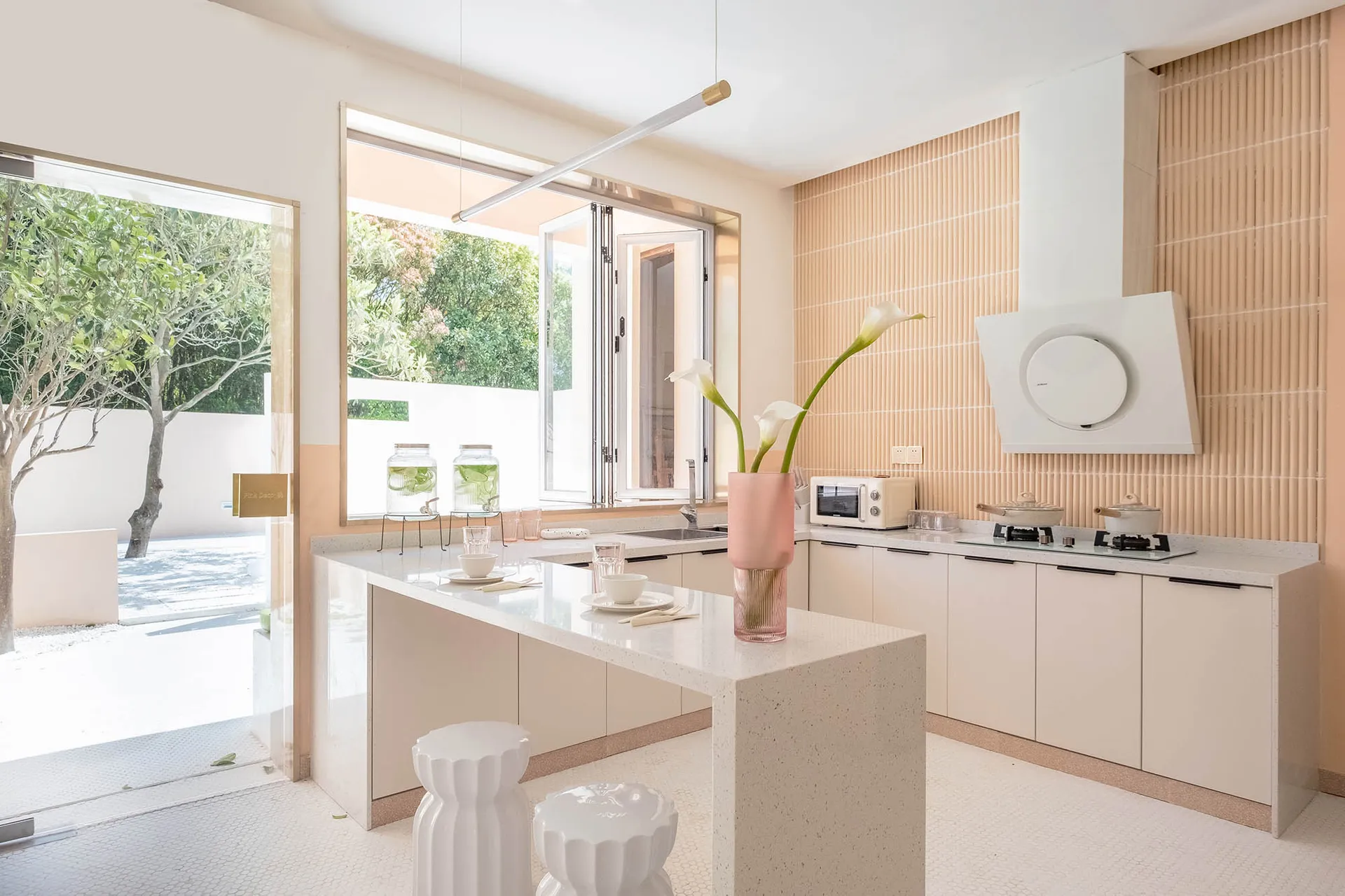 A modern minimalist residential kitchen featuring concrete countertops and backsplash with a large window overlooking greener