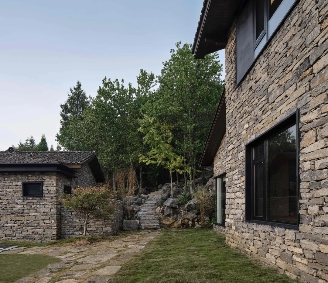 Modern architecture featuring a stone exterior with a pathway leading to a house.