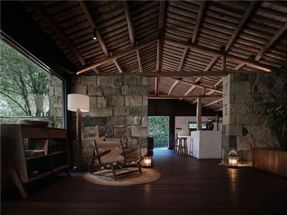 Industrial living room featuring stone walls, mortar, and concrete floor.