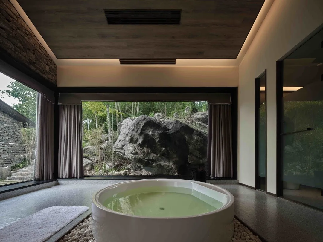 Modern bathroom featuring stone and glass materials and a view of natural surroundings.