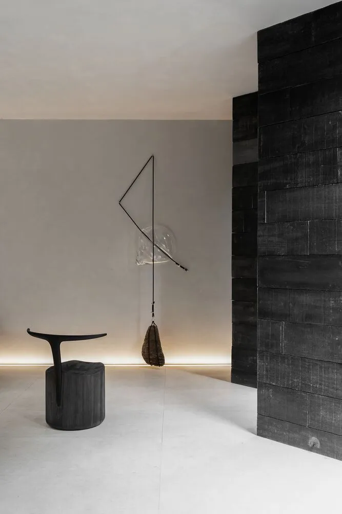 A minimalist space featuring a modern interior with concrete floors, black walls, and wooden details.