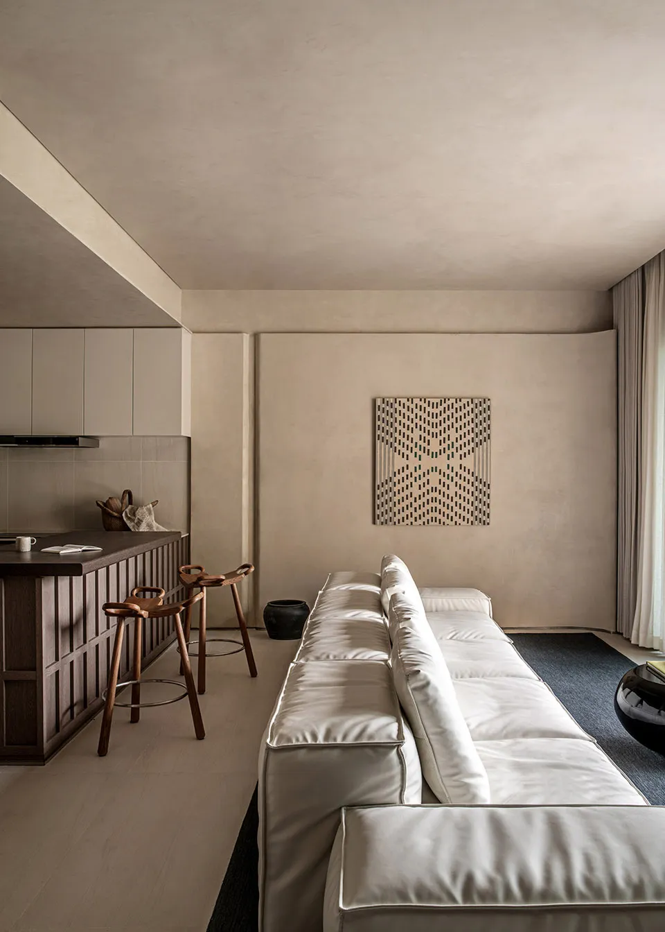 Modern living room with white sofa and geometric pattern on wall.