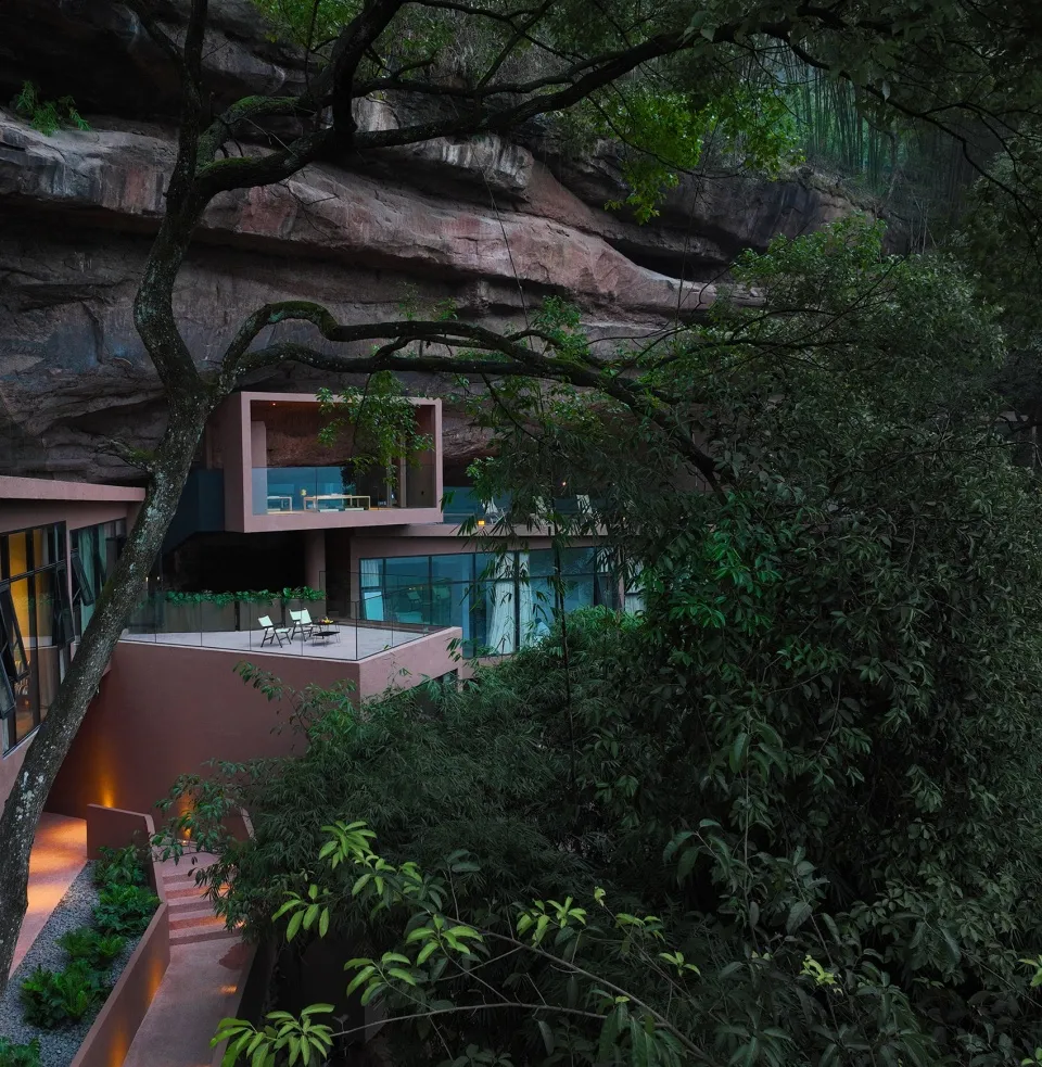 A modern house blending concrete and glass materials surrounded by nature.