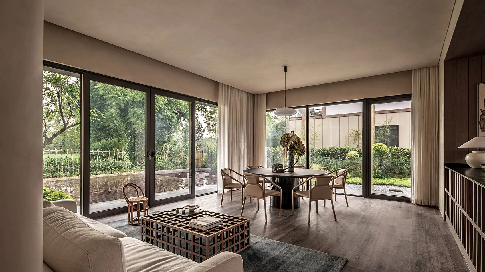 Modern interior living room with large glass windows, wooden flooring, and minimalist furniture.
