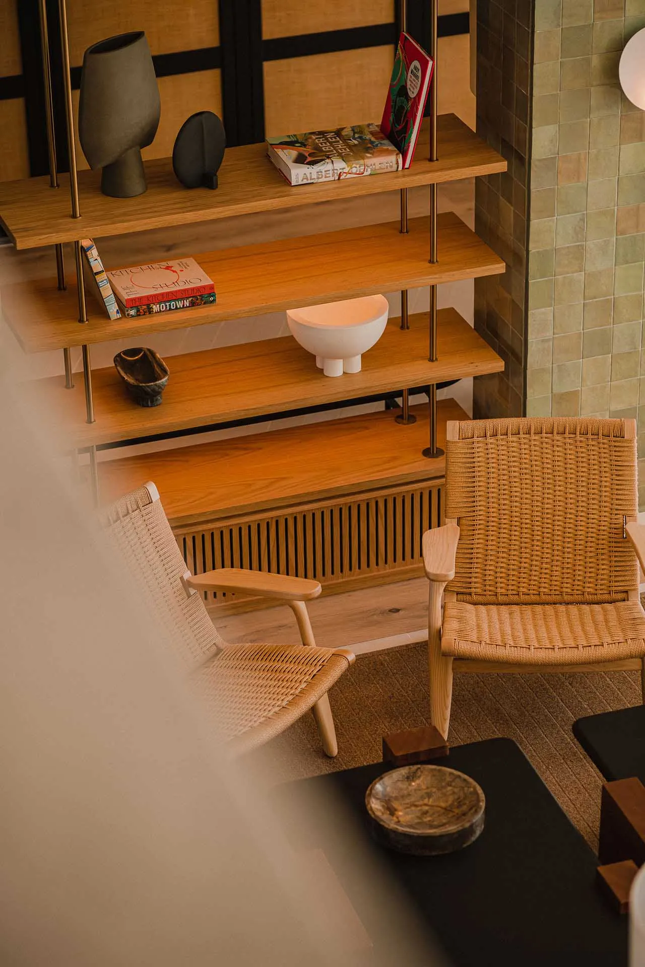 Modern living room featuring a woven-fiber chair and a wooden shelf with books and decorative items.