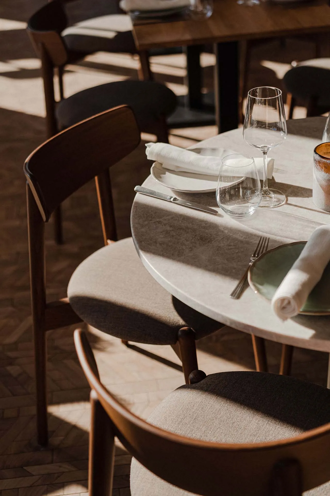 Modern restaurant table setting with white tiles, fabric upholstered chairs, white tableware, and minimalistic design element