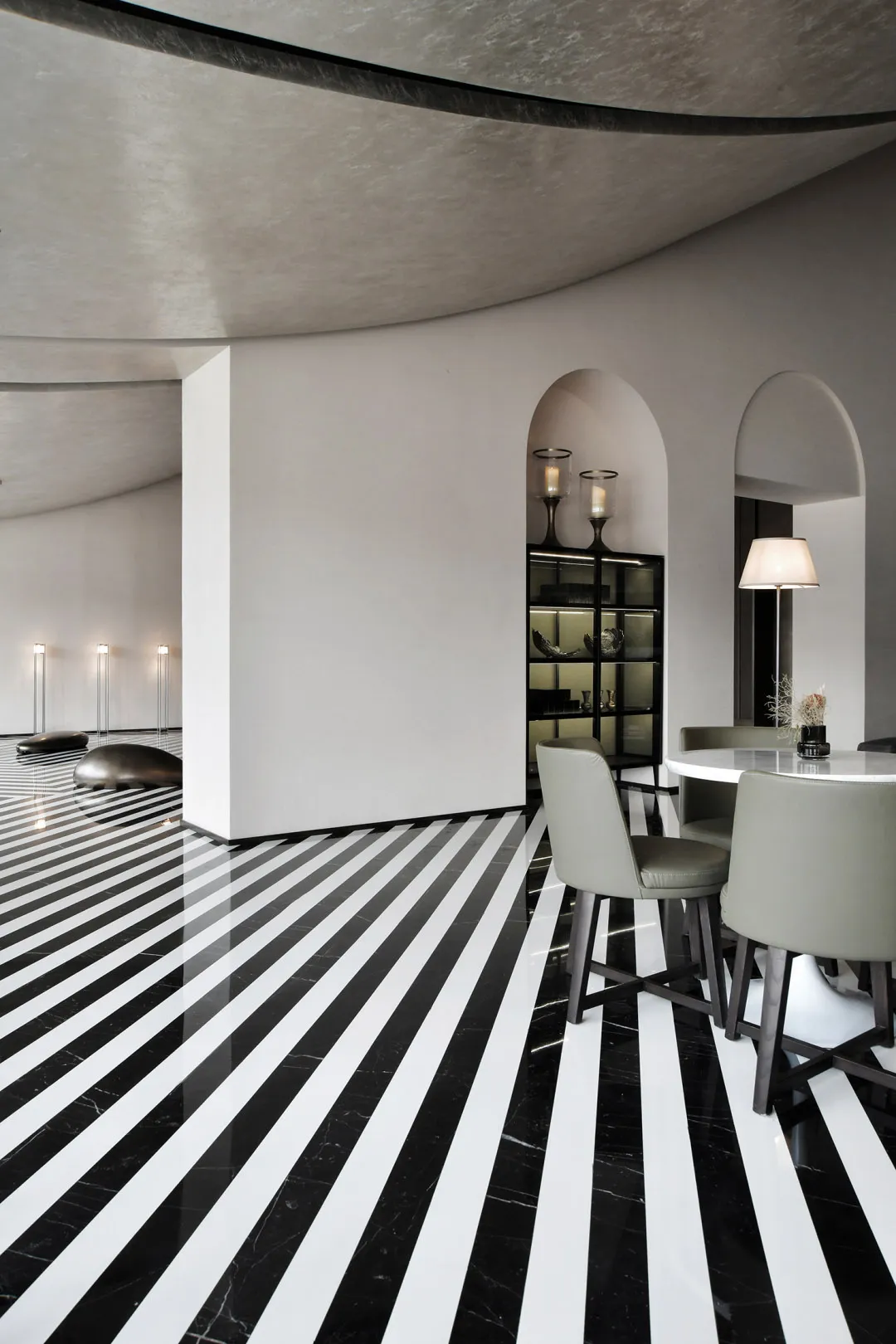 A modern dining room with concrete walls, marble flooring, and a round table with chairs.