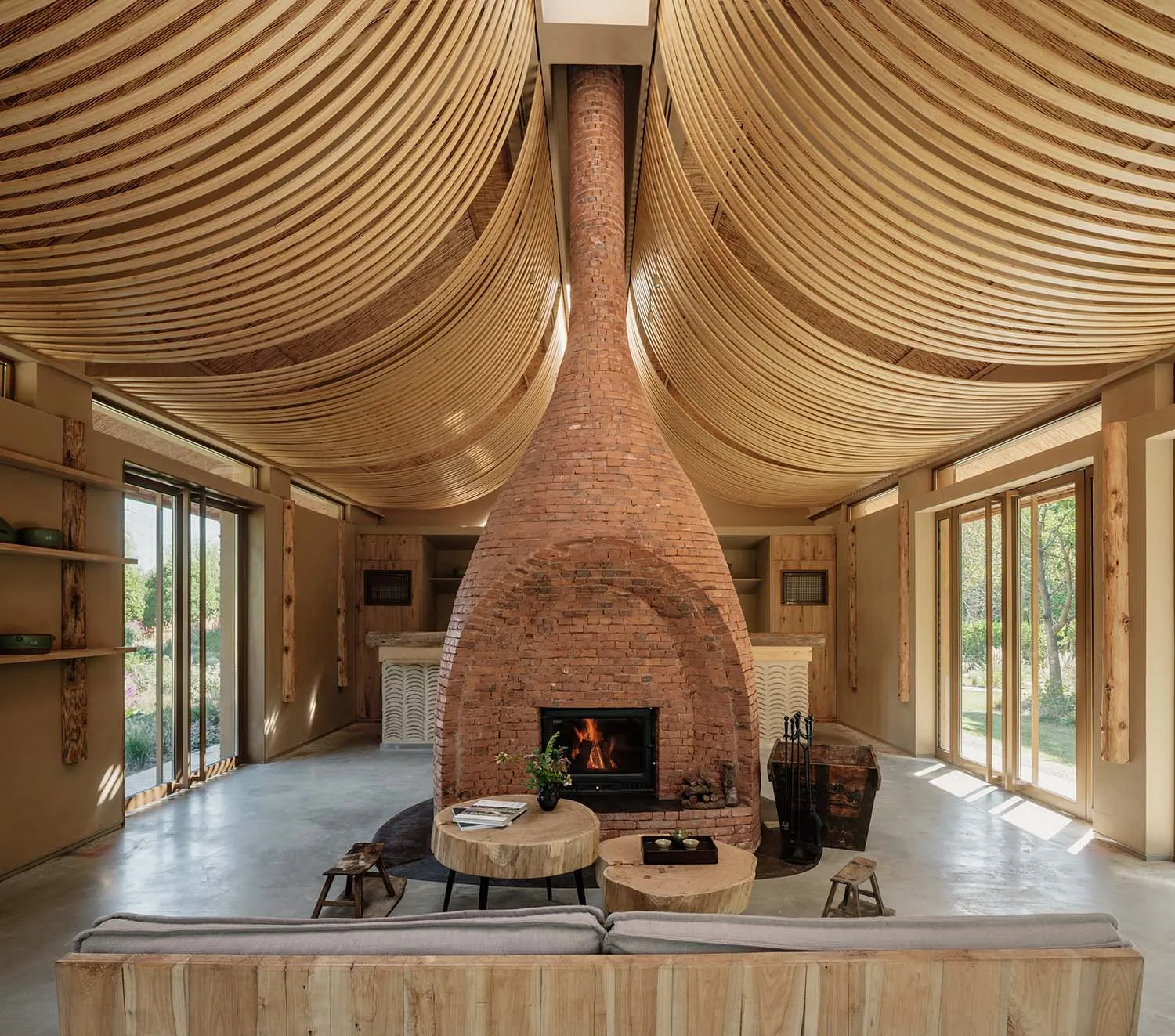 Lavish living room with a wooden ceiling, brick fireplace, and concrete floor.
