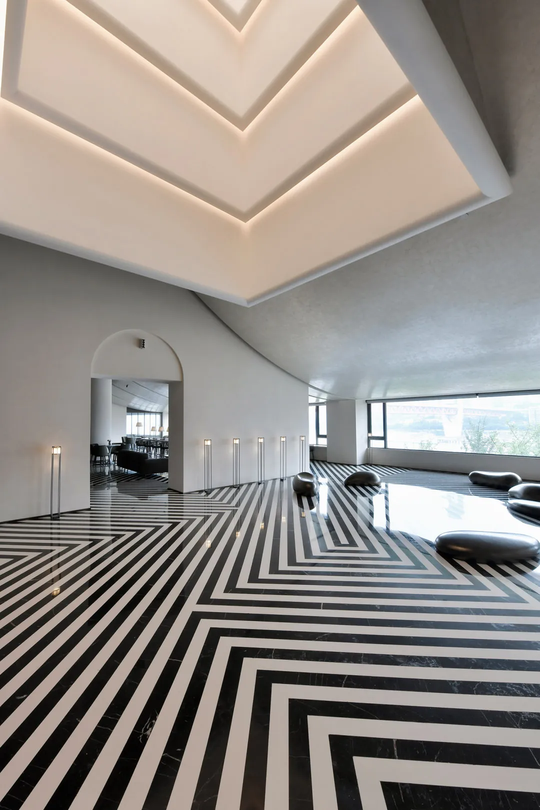A modern interior with a lobbly featuring hidden lighting, black and white marble tiles, and minimalist design
