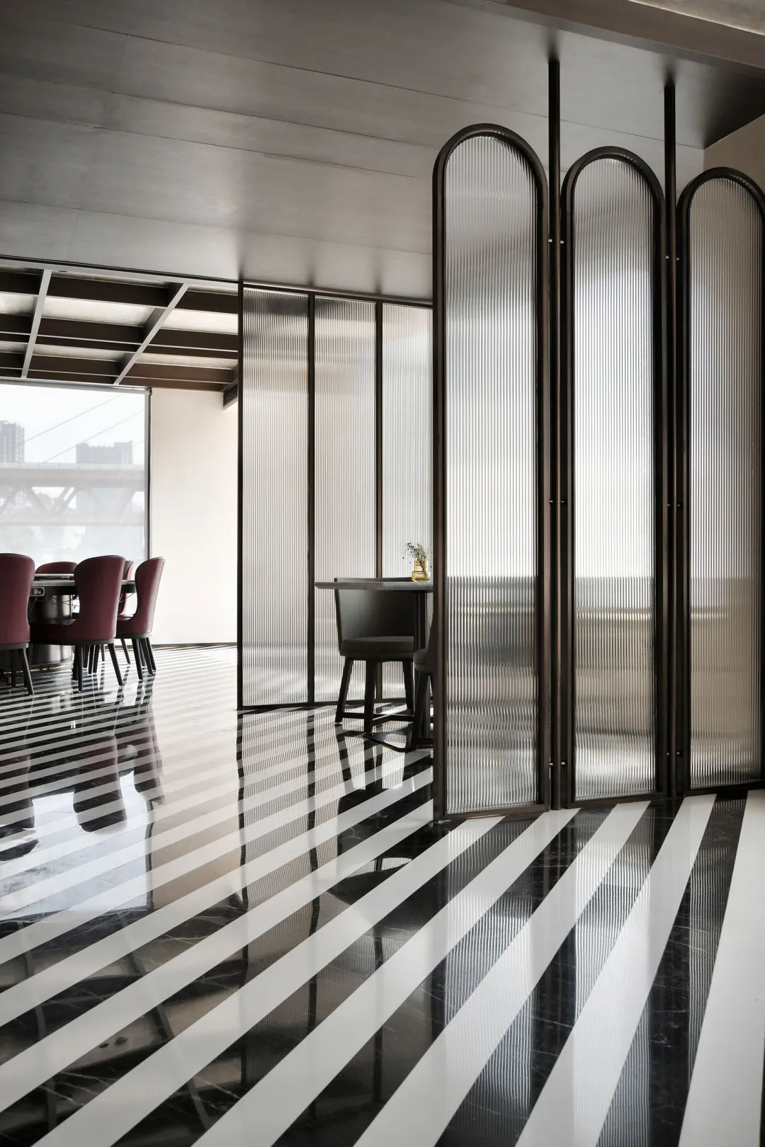 A modern restaurant interior with black and white striped flooring and glass walls.